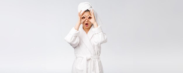 Gros plan d'une jeune femme souriante avec un geste du doigt ok sur les yeux isolé sur fond blanc