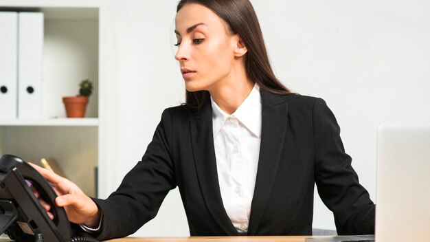 Gros plan, jeune, femme, tenue, récepteur téléphonique, bureau