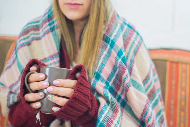 Gros plan d'une jeune fille couverte d'un foulard tenant une tasse