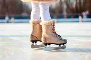 Photo gratuite gros plan de la jeune fille patinant avec des patins à glace sur une patinoire ouverte.