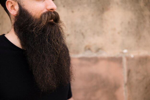 Gros plan d&#39;un jeune homme barbu contre le mur