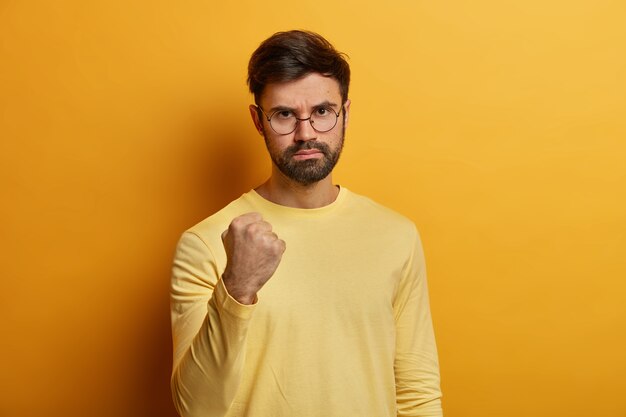 Gros plan sur le jeune homme barbu portant des lunettes isolées