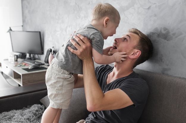 Gros plan d&#39;un jeune homme jouant avec son fils à la maison