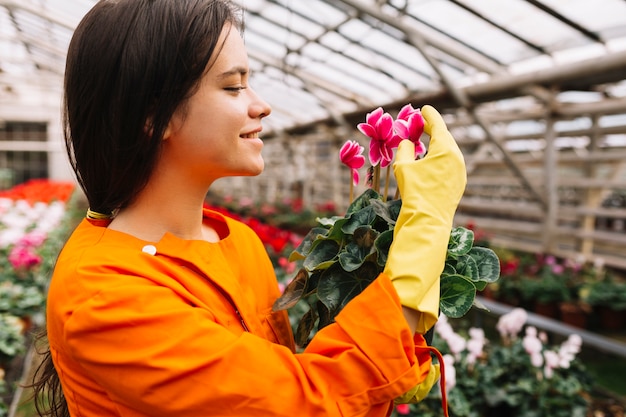 Gros plan d&#39;une jeune jardinière souriante examinant des fleurs roses