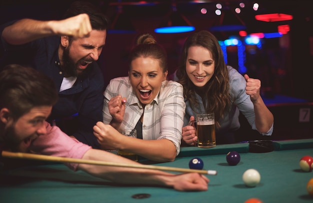 Gros plan sur les jeunes amis s'amusant tout en jouant au jeu de billard