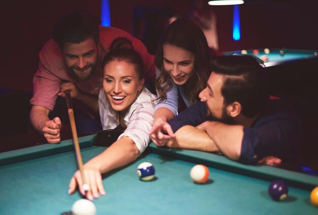 Gros plan sur les jeunes amis s'amusant tout en jouant au jeu de billard