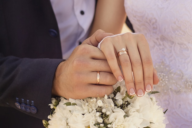 Photo gratuite gros plan de jeunes mariés se tenant la main et montrant les anneaux de mariage