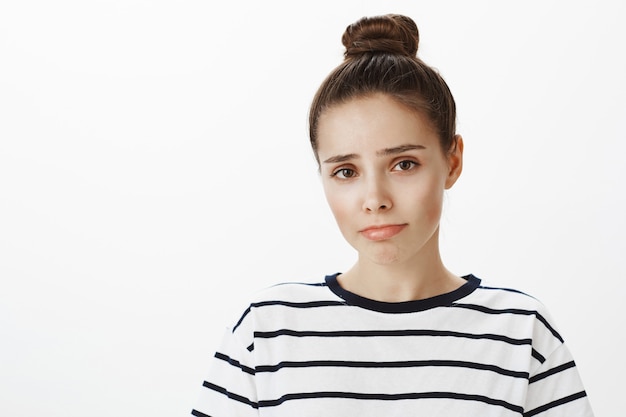 Gros plan d'une jolie fille sombre et bouleversée, faisant la moue et fronçant les sourcils, regardant avec pitié ou regret