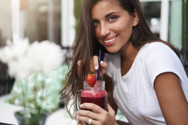 Gros plan jolie jeune femme européenne bronzée coquette siroter s