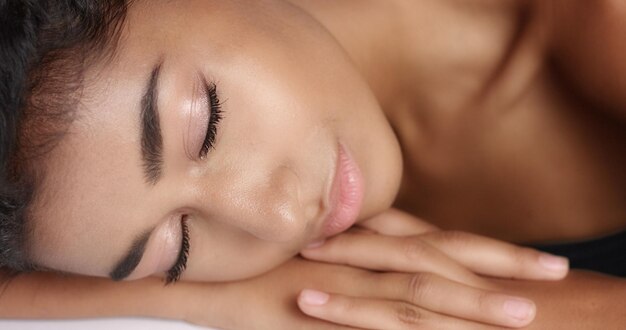 Gros plan d'une jolie jeune femme avec une peau lisse et éclatante relaxante sur une table de massage blanche