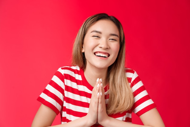 Gros plan joyeux insouciant rire jolie fille asiatique tenir la main prier remercier ami aide plaisanter smili ...