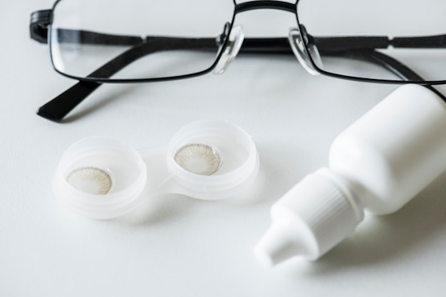 Photo gratuite gros plan sur une lentille de contact, une bouteille de solution et un concept d'optométrie de lunettes