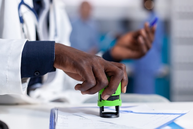 Gros plan d'une main afro-américaine tenant un timbre sur des papiers