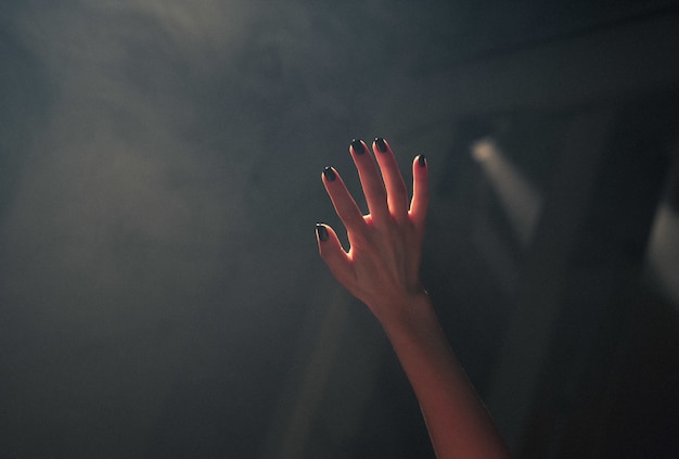 Photo gratuite gros plan de la main d'une femme couvrant les lumières avec un arrière-plan flou sombre