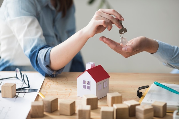 Gros plan, de, main femme, donner, clef maison, à, homme, sur, table bois