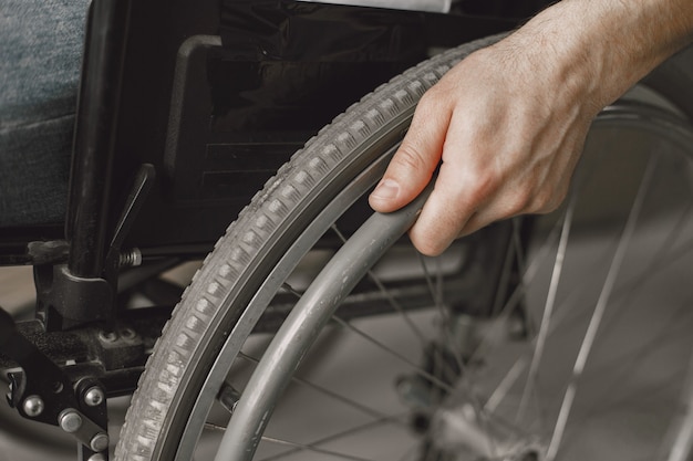 Gros plan de la main d'un homme sur la roue de son fauteuil roulant.