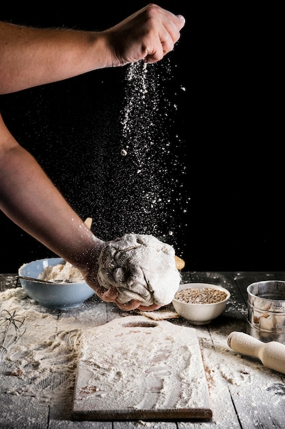 Gros plan de la main de l&#39;homme saupoudrant la farine sur la pâte