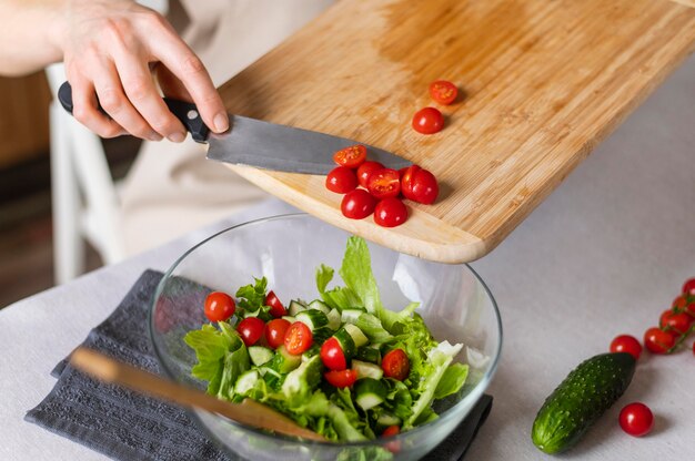 Gros plan main mettant les tomates en salade