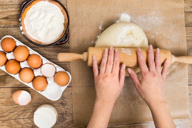 Gros plan, main, personne, roulement, boule pâte, ingrédients, table, bois