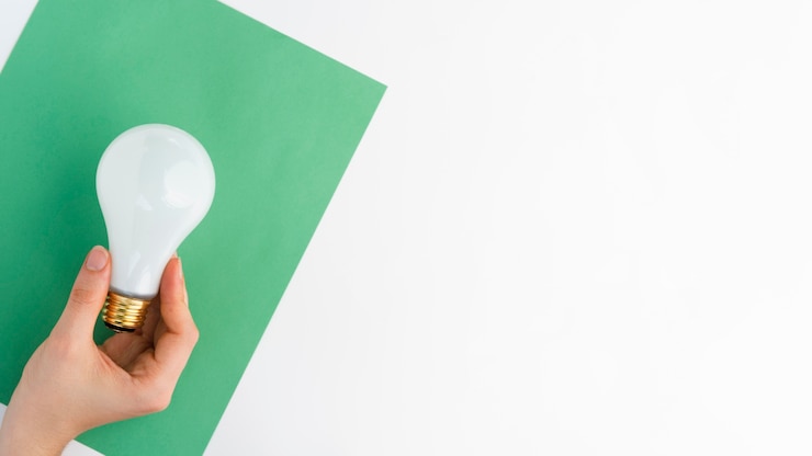 Photo gratuit gros plan, de, main, tenue, ampoule, sur, papier vert, contre, a, fond blanc