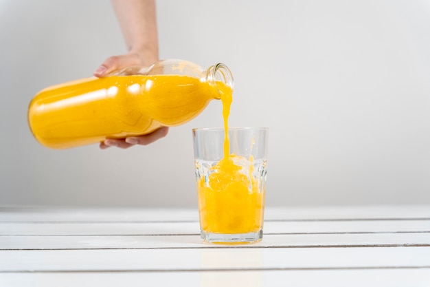 Gros plan main verser le jus d'orange en verre