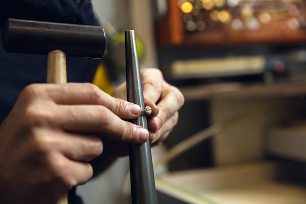 Gros plan des mains de bijoutier, orfèvres faisant de bague en or avec pierres précieuses à l'aide d'outils professionnels