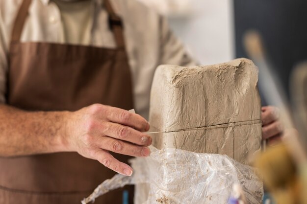 Gros plan des mains coupant l'argile