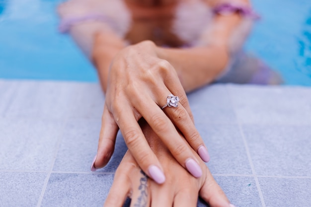 Photo gratuite gros plan des mains de la femme sur le bord de la piscine avec l'anneau au doigt
