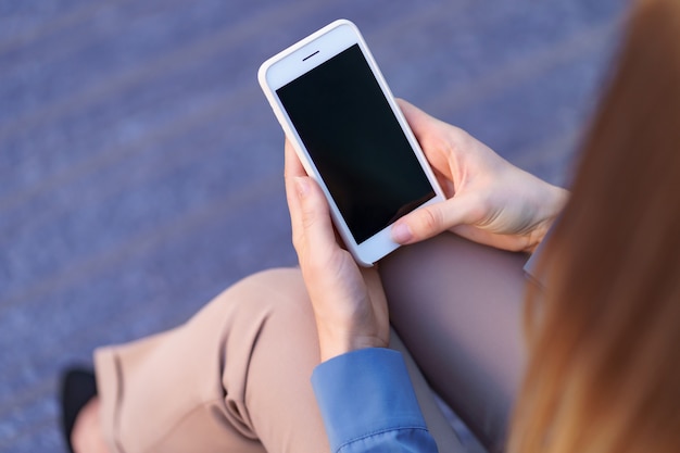 Gros plan des mains de femme tenant un smartphone avec écran noir