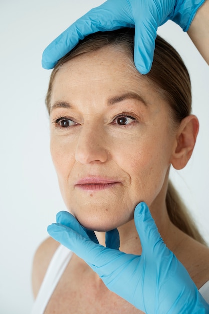 Gros plan les mains avec des gants tenant le visage de la femme souriante