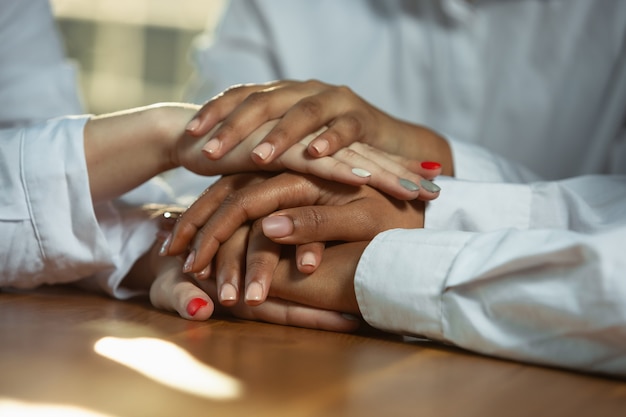 Photo gratuite gros plan des mains de l'homme afro-américain et caucasien tenant sur une table en bois