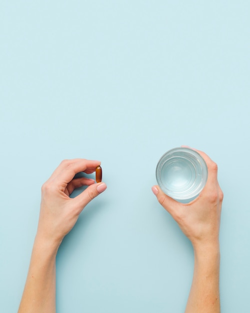 Photo gratuite gros plan des mains avec de la pilule et de l'eau