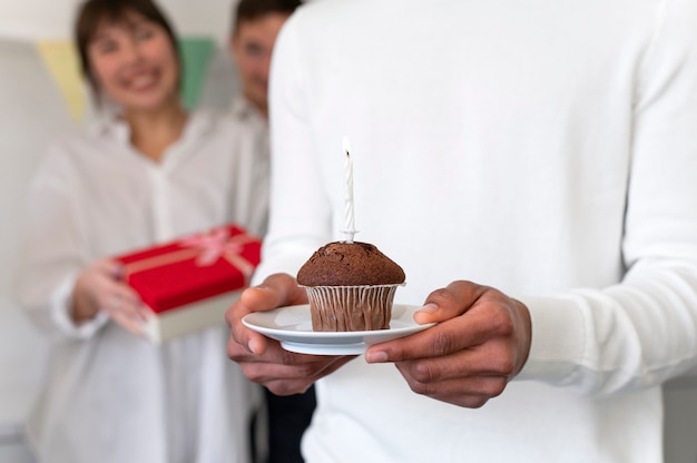 Gros plan des mains tenant une assiette avec un cupcake