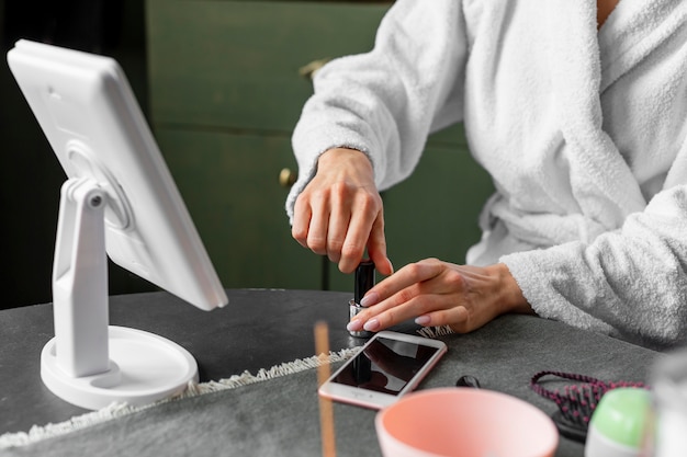 Gros plan des mains tenant une bouteille de vernis à ongles