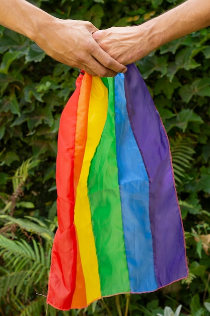 Gros plan des mains tenant le drapeau de la fierté gay