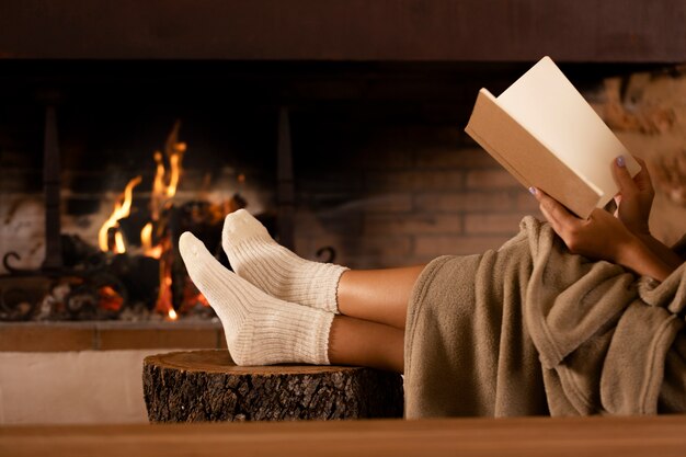 Gros plan sur les mains tenant un livre au coin du feu