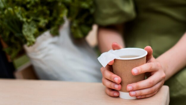 Gros plan des mains tenant une tasse de thé bio