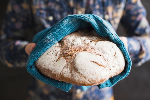 Photo gratuite gros plan, mains, tenue, pain cuit, enveloppé dans serviette bleu