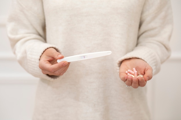 Photo gratuite gros plan des mains avec test de grossesse et pilules