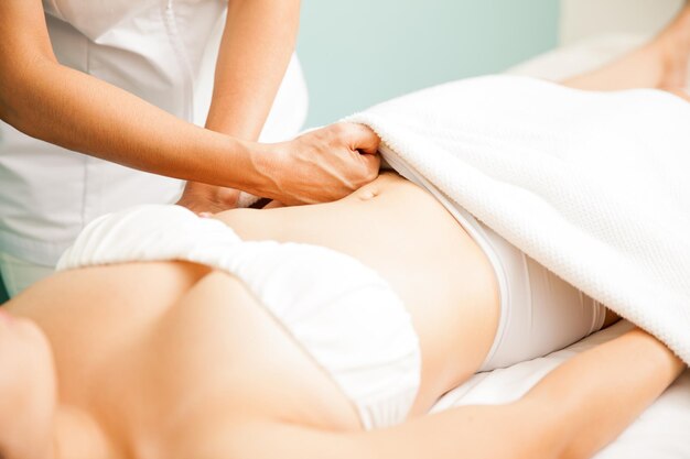 Gros plan des mains d'une thérapeute donnant un massage des tissus profonds à un client dans un spa