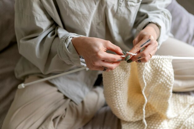 Gros plan des mains à tricoter avec des tricoteuses