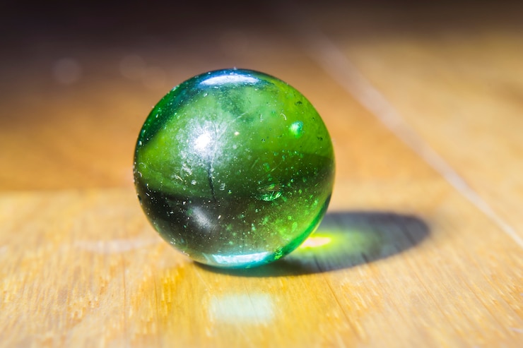 Photo gratuit gros plan d'un marbre vert au-dessus d'une table en bois