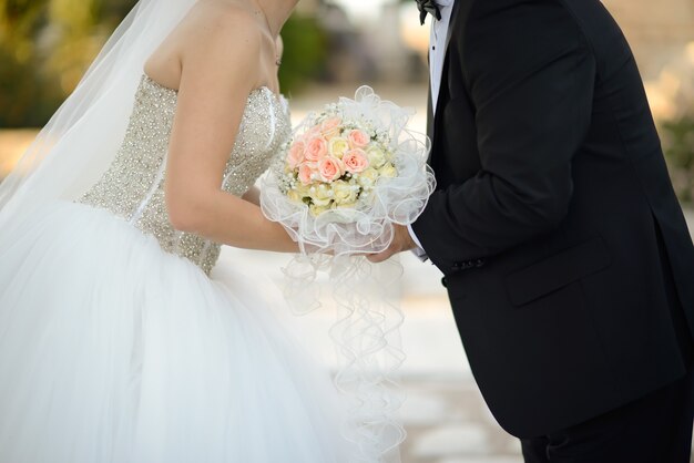 Gros plan d'une mariée et le marié s'embrassant tout en tenant le beau bouquet