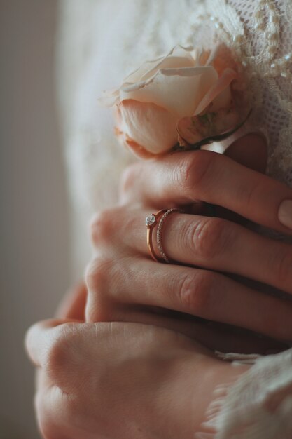 Gros plan d'une mariée portant une belle bague en diamant et tenant une rose