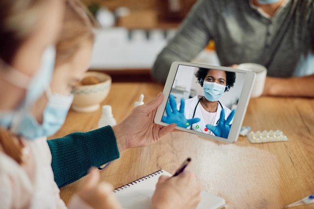 Gros plan d'un médecin afro-américain ayant un appel vidéo avec ses patients en raison d'une pandémie de coronavirus