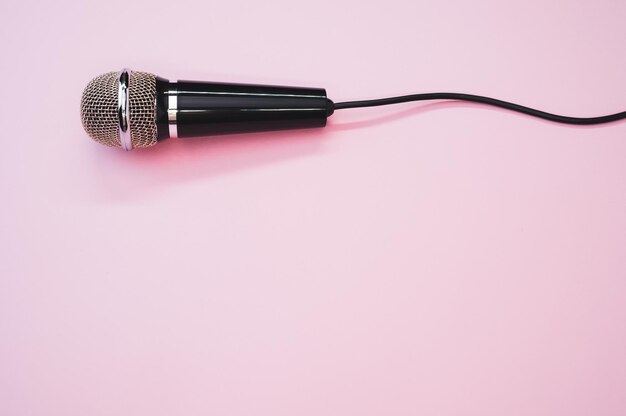 Gros plan d'un microphone avec un fil isolé sur un fond rose avec une ombre