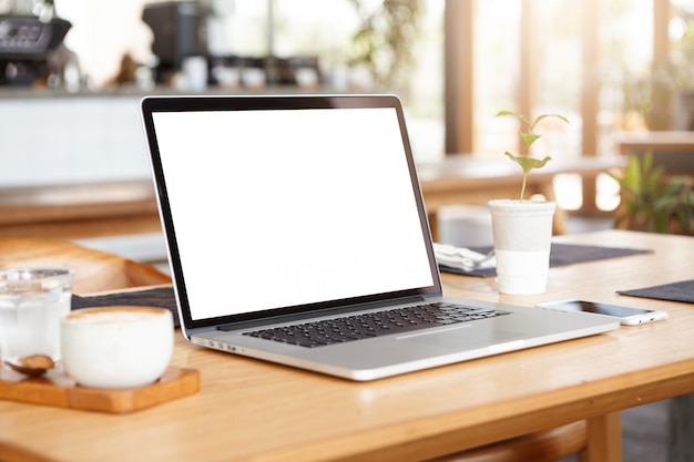 Gros plan minimaliste de l'ordinateur portable générique et des accessoires de travail reposant sur une table en bois