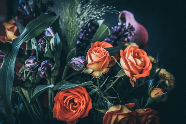 Gros plan sur la mise au point sélective d'un bouquet de fleurs avec des roses orange et des fleurs violettes