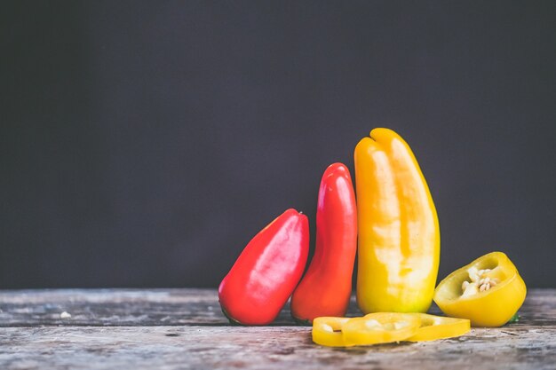 Gros plan de mise au point sélective tourné de piments jaunes et rouges dans un tas sur une surface en bois