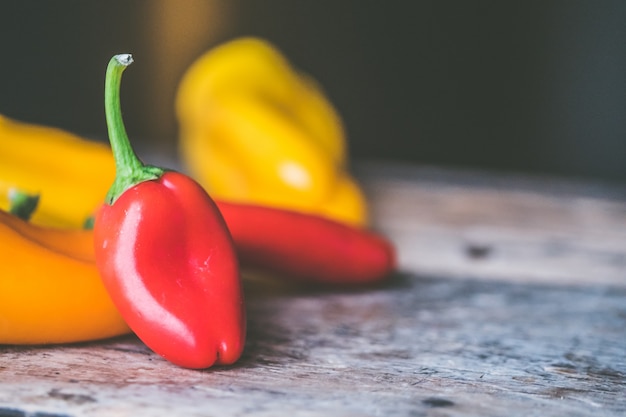 Gros plan de mise au point sélective tourné de piments jaunes et rouges dans un tas sur une surface en bois